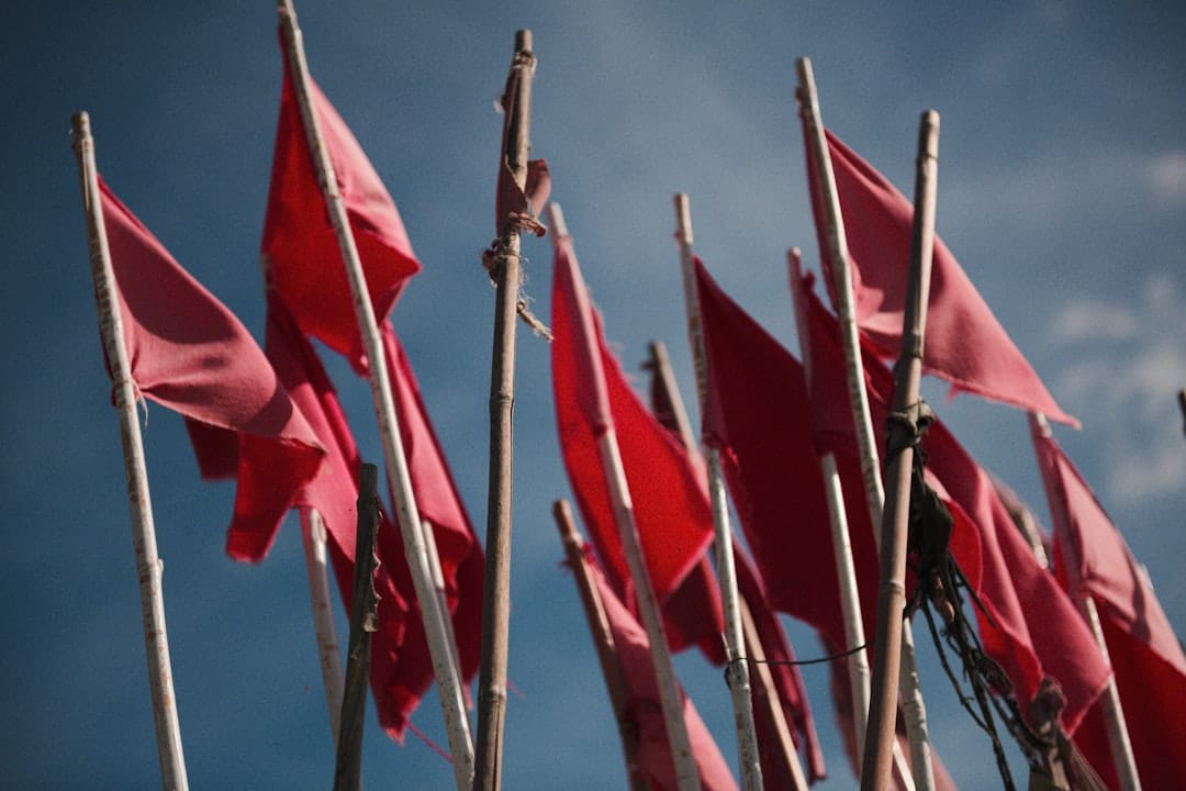 Poles with red flags under blue sky during daytime