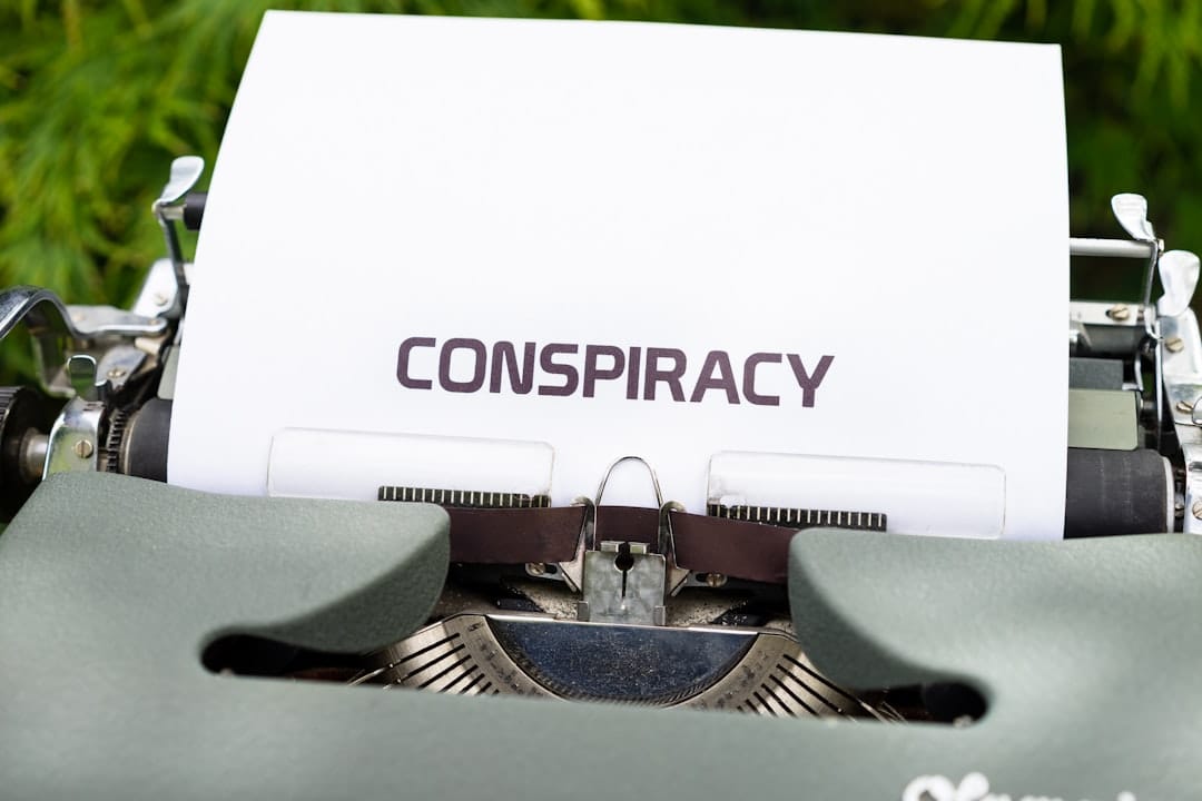 A close up of a typewriter with the word conspiracy on it
