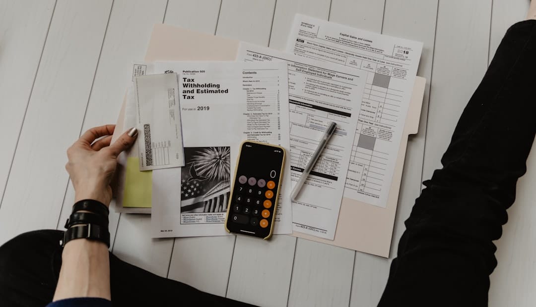 Person holding paper near pen and calculator