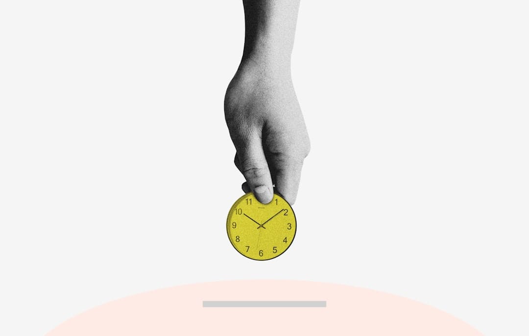 Person holding yellow round analog clock
