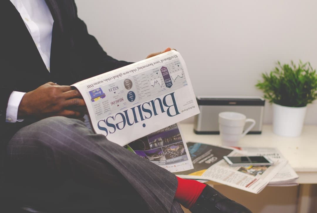 Person sitting near table holding newspaper