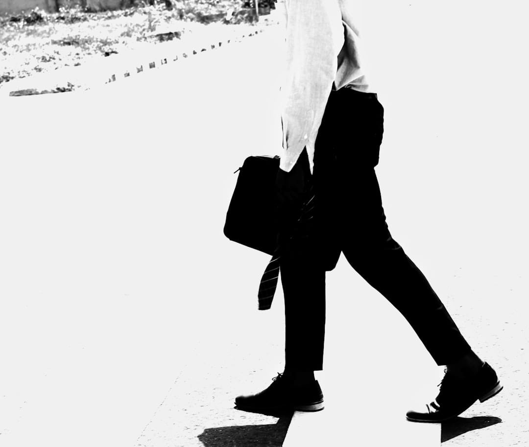 Man in white dress shirt and black pants crossing street